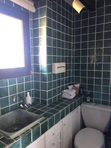 La salle de bains est pourvue de carrelage bleu, d'un lavabo et de toilettes. dans l'établissement Apartment du Pic de l 'Ours, à Théoule-sur-Mer