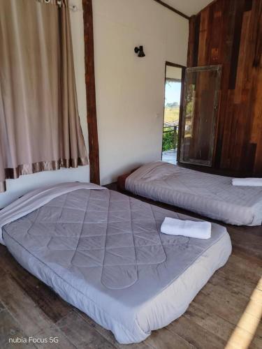 two beds in a room with a window at Bannuea Local Life in Ban Nam Lat