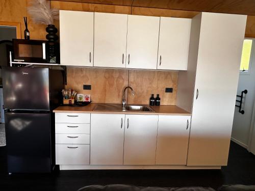 a kitchen with white cabinets and a stainless steel refrigerator at Moana Lakeview Chalet in Moana