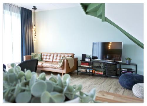 a living room with a couch and a flat screen tv at Waterluxe Villa in Stavoren in Stavoren