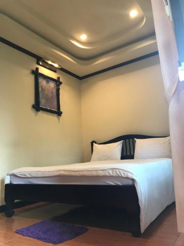 a bedroom with a bed with white sheets and a window at บ้านต้นรักษ์ BanTonRuk Takuapa in Takua Pa