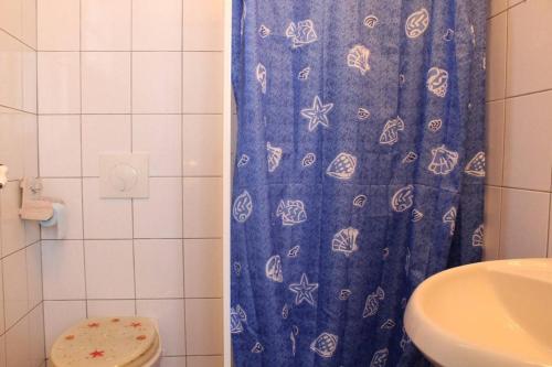 une salle de bain avec un rideau de douche bleu et des toilettes dans l'établissement Maison 2 pièces 2 couchages Dolus d'Oléron DDO000-022, à Dolus-d'Oléron