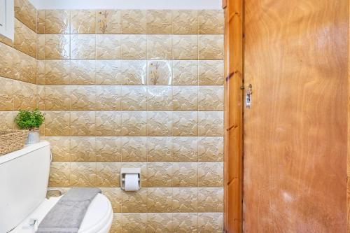 a bathroom with a toilet and a wooden door at Dolphin villa 1 in Gaios
