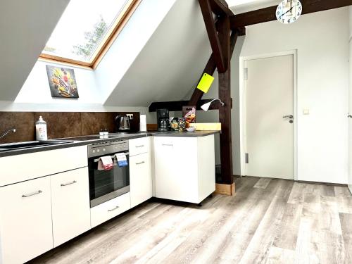 an attic kitchen with white cabinets and a window at Ferienwohnung in Schkeuditz in Schkeuditz