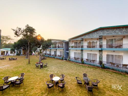 a group of tables and chairs in front of a building at Wonderwood Corbett Resort -1min walk to River with Deep Jungle Trail in Rāmnagar