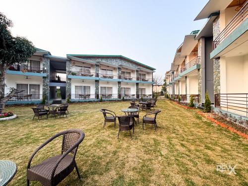 a group of tables and chairs in a courtyard at Wonderwood Corbett Resort -1min walk to River with Deep Jungle Trail in Rāmnagar