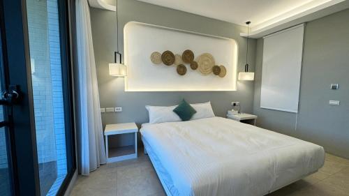 a bedroom with a large white bed and two tables at 禾夏民宿Her Shot Inn in Hengchun