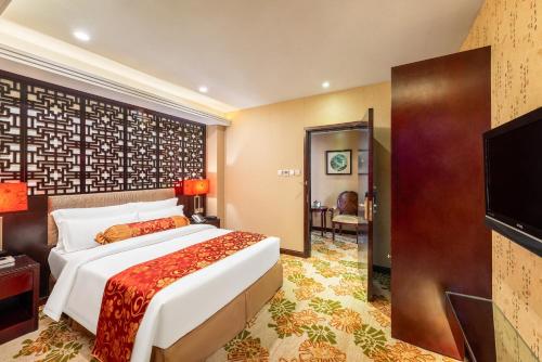 a hotel room with a bed and a flat screen tv at Hotel Metropole in Macau