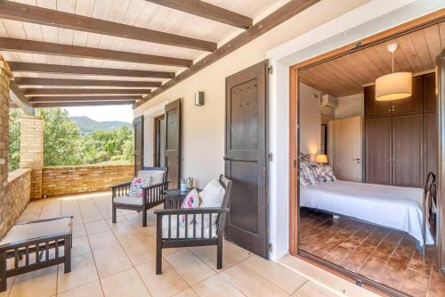 a bedroom with a bed and chairs on a patio at Villa Antinoti in Agía Aikateríni