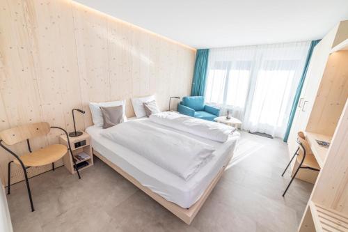 a bedroom with a large bed and a blue chair at Hotel Seebüel in Davos