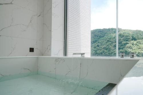 a white bathroom with a tub and a window at Izumi Boutique Hotel in Puli