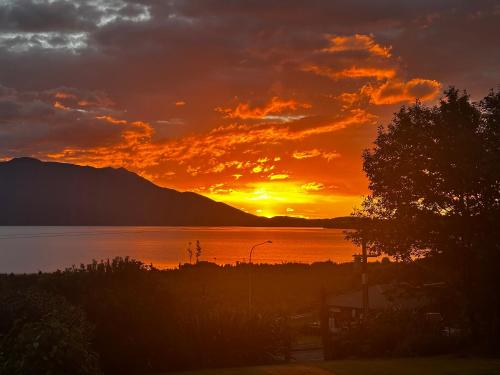 a sunset over a body of water with a tree at Moana Lakeview Chalet in Moana