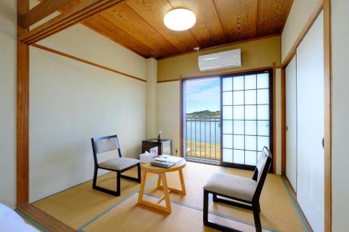 a room with two chairs and a table and a window at 鹿鳴館 in Yurihama