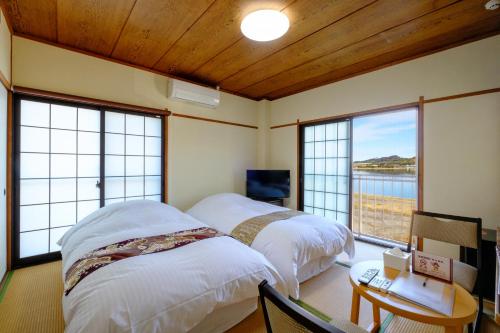 two beds in a room with a view of the water at 鹿鳴館 in Yurihama