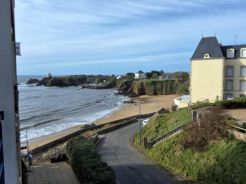 une vue d'une plage avec un bâtiment et l'océan dans l'établissement Résidence des dunes, à Clohars-Carnoët
