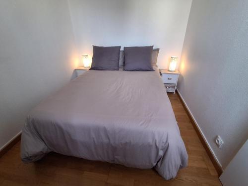 - un lit dans une petite chambre avec deux lampes dans l'établissement Résidence des dunes, à Clohars-Carnoët