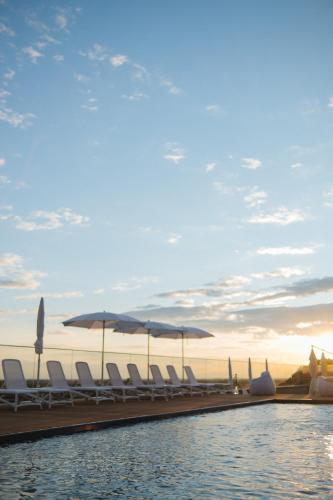 a pool with chairs and umbrellas and the ocean at WHITE HILLS HOTEL spa&sport in Uzhhorod