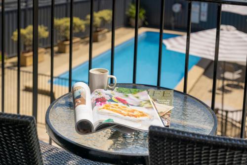 a glass table with a book and a drink and food on it at Ozone Hotel Kangaroo Island in Kingscote