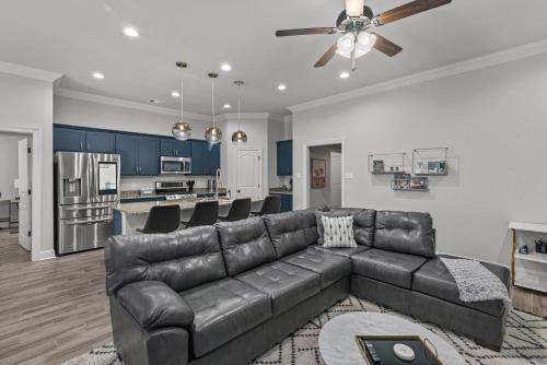 a living room with a leather couch and a kitchen at Aurora Haven - TV in each room in Shreveport