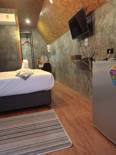 a bedroom with a bed and a tv on a wall at เรินนายหัว by KOYAD RESORT in Ban Wat Khao