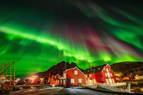 an aurora over a town with houses and buildings at Ure Lodge in Sennesvik