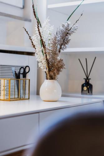 a white vase with dried flowers on a counter at The Penthouse Basel in Basel