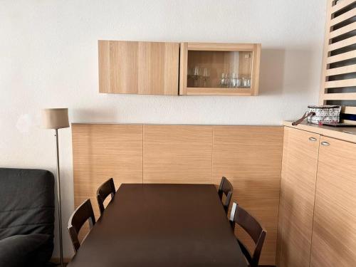 une cuisine avec une table et des chaises noires ainsi qu'une armoire dans l'établissement Chalets du Verdon 3302 - pied des pistes -6 pers, à La Foux
