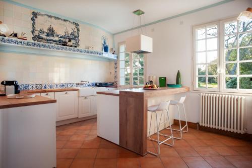 une cuisine avec des armoires blanches et un îlot avec des tabourets dans l'établissement Ty Launay - Maison familiale vue mer, à Ploubazlanec