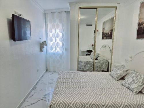a white bedroom with a bed and a mirror at Habitaciones Torremolinos in Torremolinos