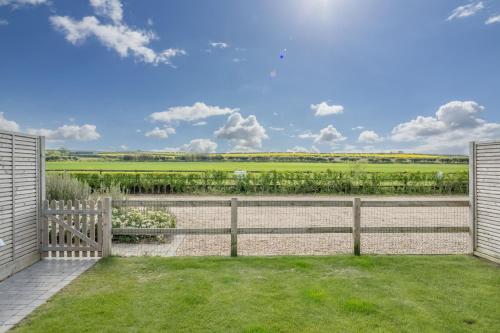 a backyard with a fence and grass at Kingfishers Cove 4 in Titchwell