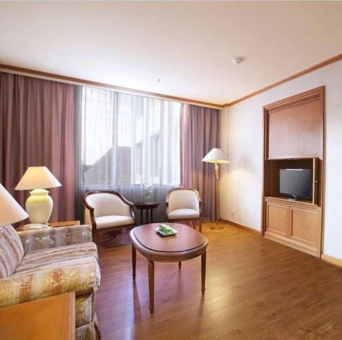 a living room with a couch and a table and a tv at Hotel Sahid Jaya Solo in Solo