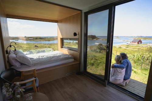 Zwei Leute schauen aus dem Fenster eines winzigen Hauses in der Unterkunft Smøla Sleeping Experience Re-Treats in Steinsøynes