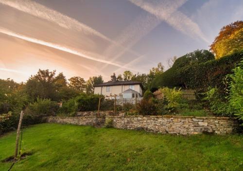 a house behind a stone wall in a yard at Burleigh Court Hotel in Stroud