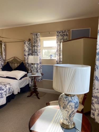 a bedroom with a bed and a table with a lamp at Rossmanagher House in Bunratty