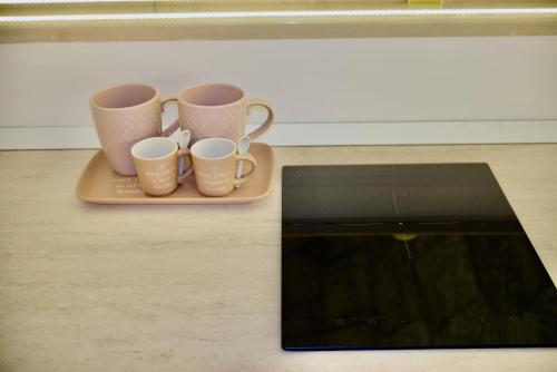 a tray with three coffee mugs and a tablet at La Conchiglia in Molfetta