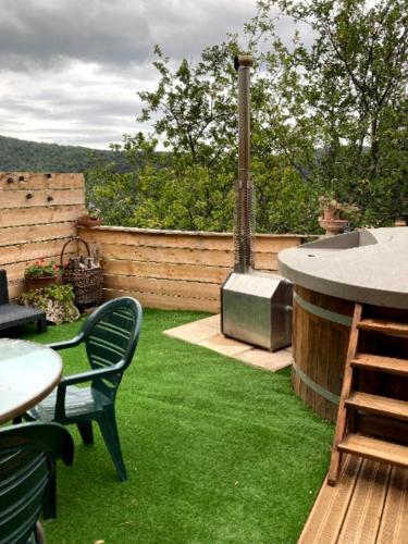 a backyard with green grass and a grill at Mas Vizern avec bain nordique in Taillet
