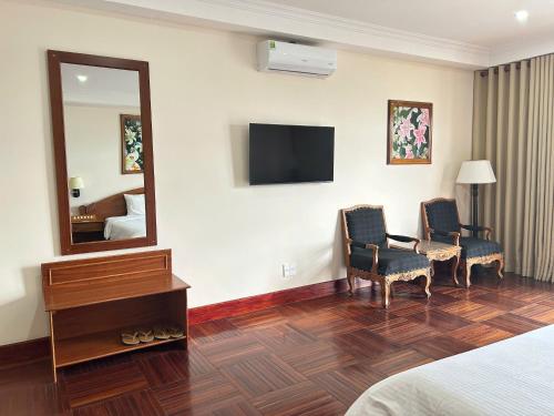 a hotel room with two chairs and a mirror at Khách Sạn Mường Thanh Grand Gia Lai in Pleiku