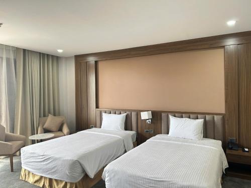 a hotel room with two beds and a chair at Khách Sạn Mường Thanh Grand Gia Lai in Pleiku