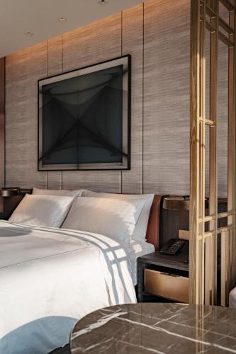 a bedroom with a bed and a tv on the wall at Conrad Shenzhen, the first art museum hotel in Greater Bay Area with the stunning bay and sunset view in the hotel terrace in Shenzhen