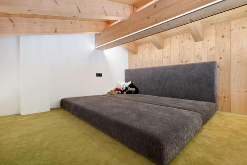 a large gray bed in a room with wooden ceilings at Chalet Berg in Selva dei Molini