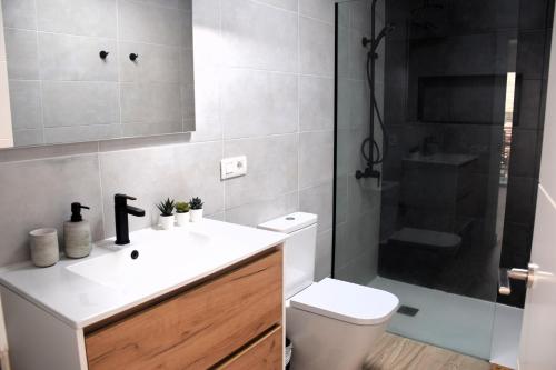 Un baño con inodoro, lavabo y ducha. en La Terraza del Faro, en Mazo