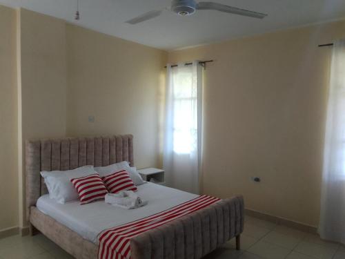 Un dormitorio con una cama con dos almohadas rojas y blancas. en SHE Homes, en Mombasa