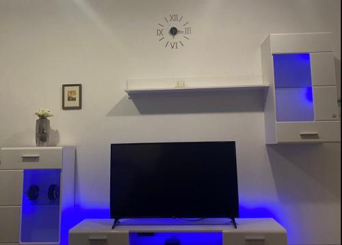 a living room with a tv and a clock on the wall at Luxe Central Living Apartment in Debrecen