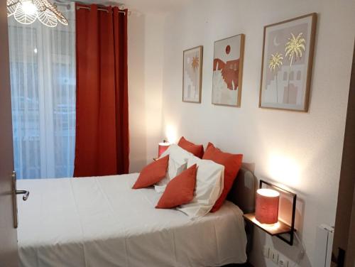 une chambre avec un lit avec des oreillers rouges et blancs dans l'établissement B010 Appartement Disneyland Paris France, à Montévrain