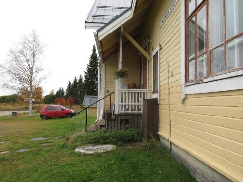 a porch of a yellow house with a red car at Kukkolan vanha koulu in Kukkola