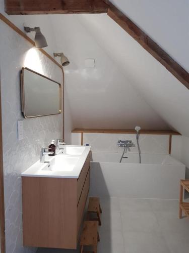 La salle de bains est pourvue d'un lavabo et d'une baignoire avec un miroir. dans l'établissement Maison familiale avec piscine Les Petites Dalles, à Sassetot-le-Mauconduit