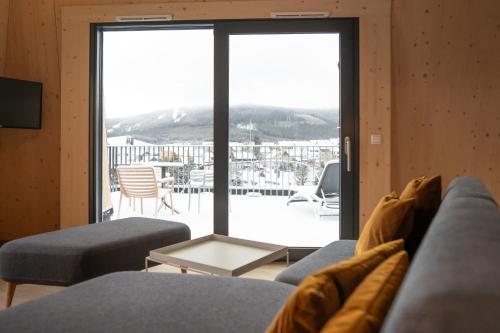 a living room with a couch and a sliding glass door at Summit of Saxony Resort Oberwiesenthal in Kurort Oberwiesenthal