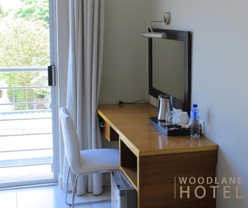 a desk with a television and a chair in a room at Woodlane Hotel in Gaborone