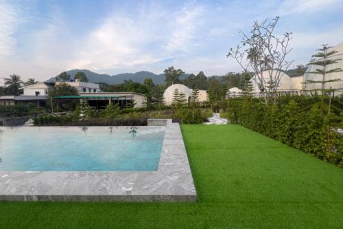 a swimming pool with green grass and buildings at Sunny Side Resort Koh Tao in Koh Tao