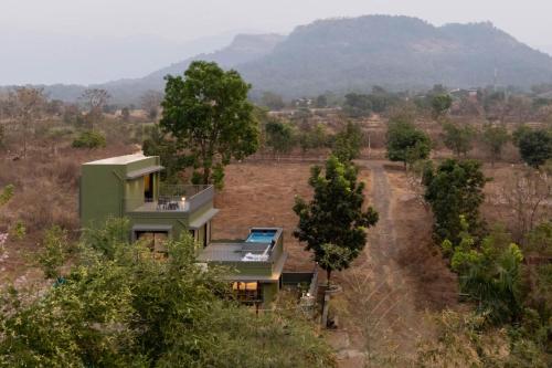 a house in the middle of a field with trees at Eden Springs by VEO - Part of StayVista in Karjat
